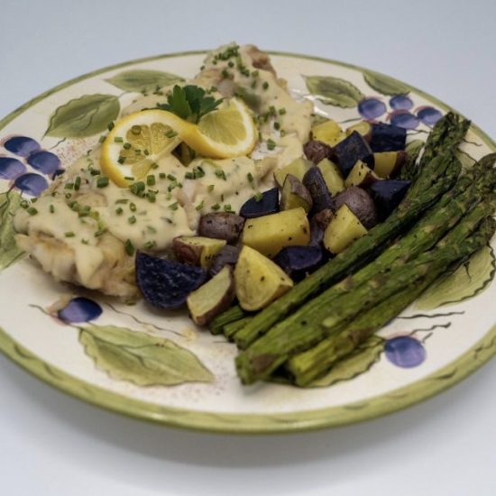 Walleye fillets plated with asparagus, potatoes and a twist of lemon.