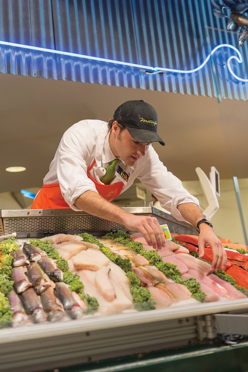 Fish monger organizing fish for retail sale.
