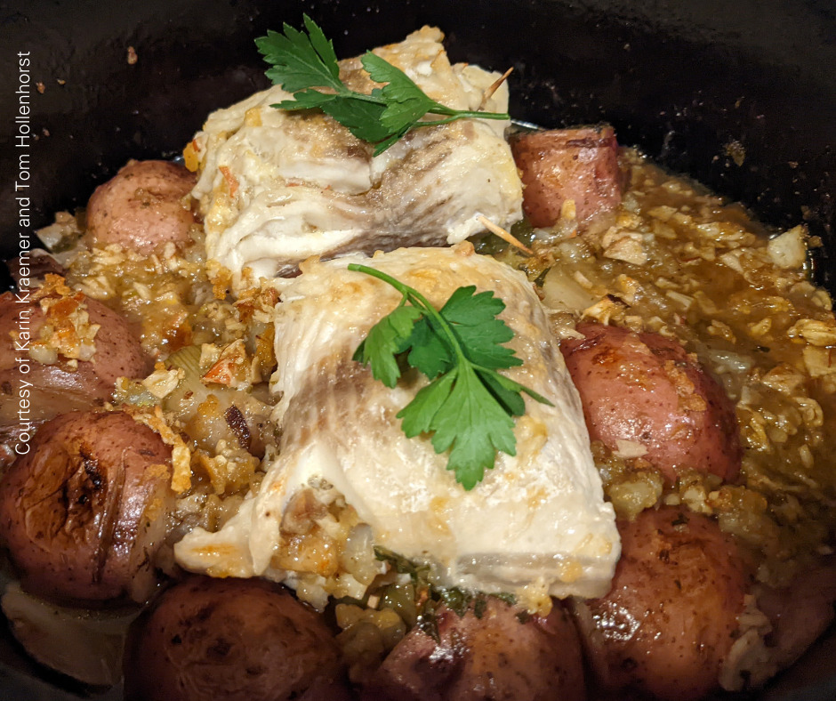 Two stuffed lake whitefish fillets over potatoes and leeks in a cast iron pot.