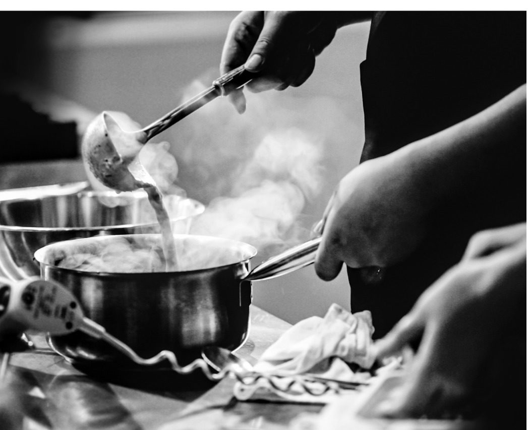 people cooking a steaming fish dish