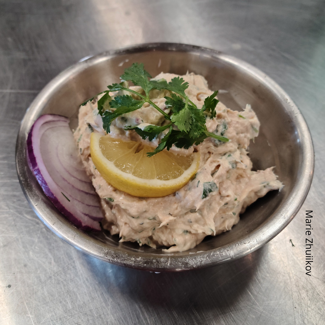 fish spread in a metal bowl with lemon, parsley and red onion garnish